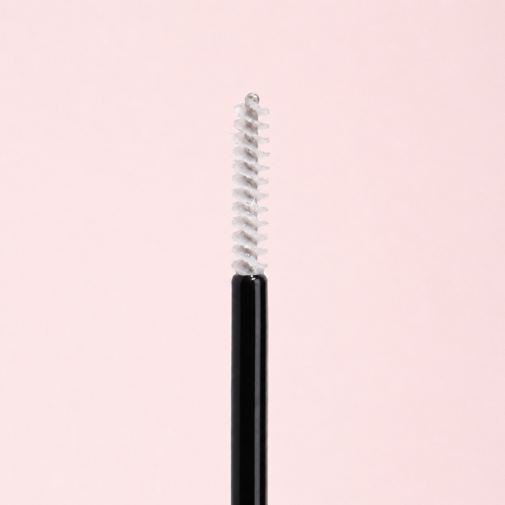 Black eyeliner pencil with silver cap on a light pink background