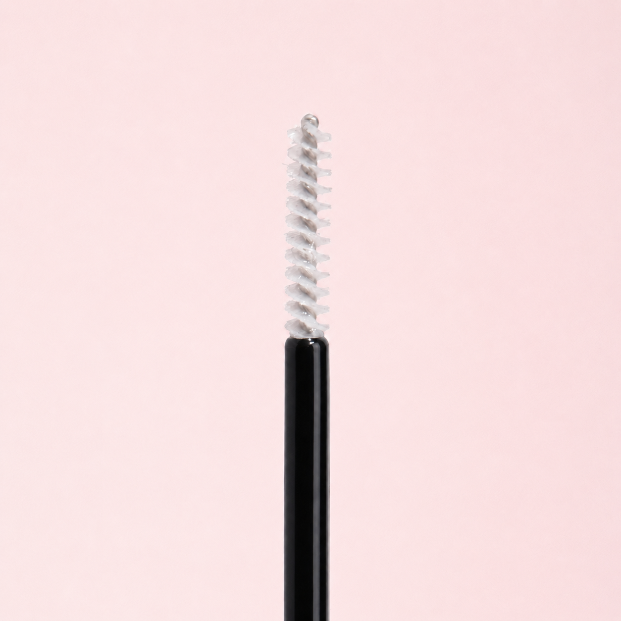 Black eyeliner pencil with silver cap on a light pink background