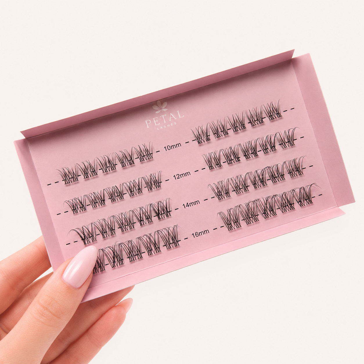 Set of false eyelashes in a pink case held by a hand on a white background