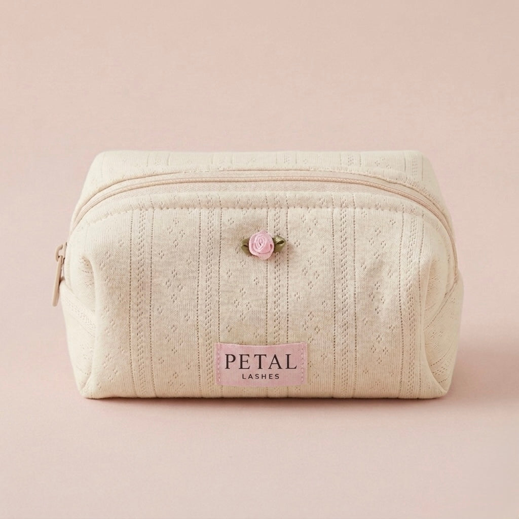 Cream-colored makeup bag with 'Petal Lashes' branding on a light pink background