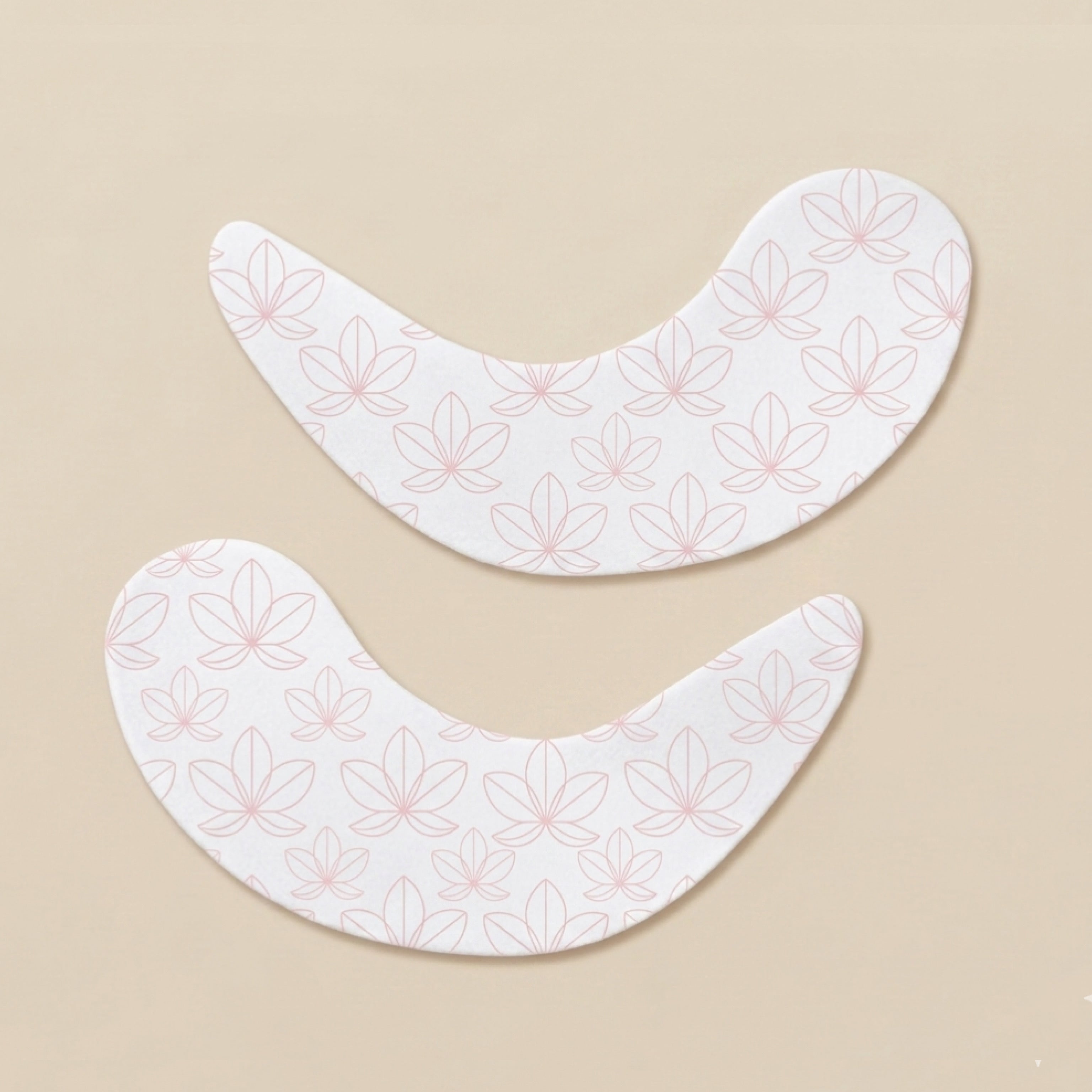 Two lotus patterned undereye patches on a creamy beige background.