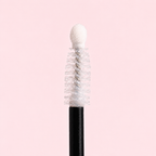 Mascara brush with white bristles on a pink background