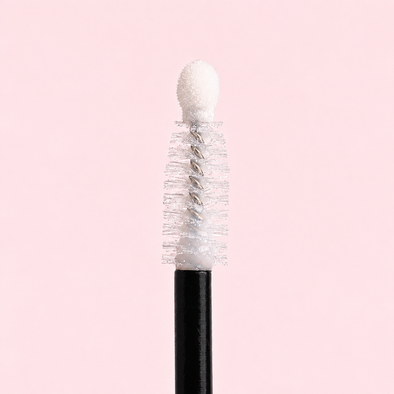 Mascara brush with white bristles on a pink background